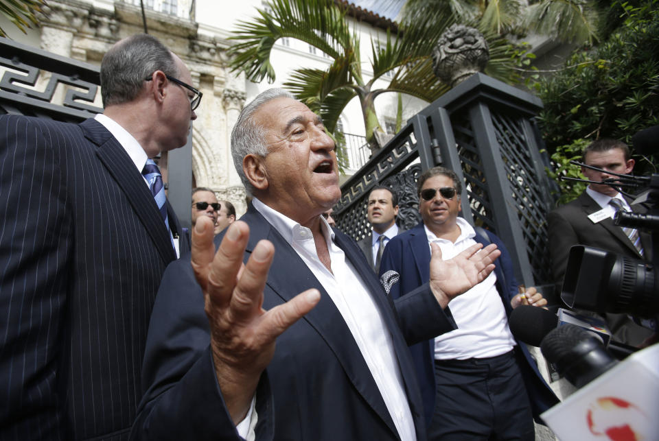 Joe Nakash, center, with VM South Beach LLC, speaks to the media after having placed the winning bid of $41.5 million for the South Beach mansion that once belonged to Gianni Versace, at rear, during an auction, Tuesday, Sept. 17, 2013 in Miami Beach, Fla. Gianni Versace bought the property in 1992. He was fatally shot on its steps in 1997 by a serial killer. His family sold it in 2000, and it operated as a private club and then as a boutique hotel until earlier this year. (AP Photo/Wilfredo Lee)