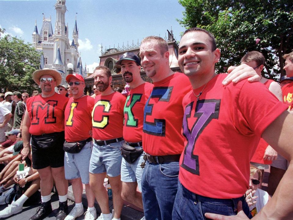 Six gay men spell out the word "Mickey" on their shirt