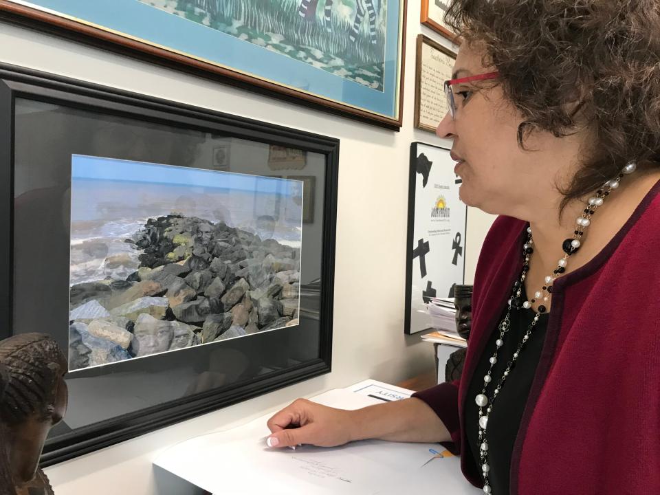 Cassandra Newby-Alexander, history professor and dean of Norfolk State University's College of Liberal Arts looks at a photograph entitled "The Ancestors" by Elvira Welbeck inside her office on Friday, Nov. 22, 2019 in Norfolk, Virginia.