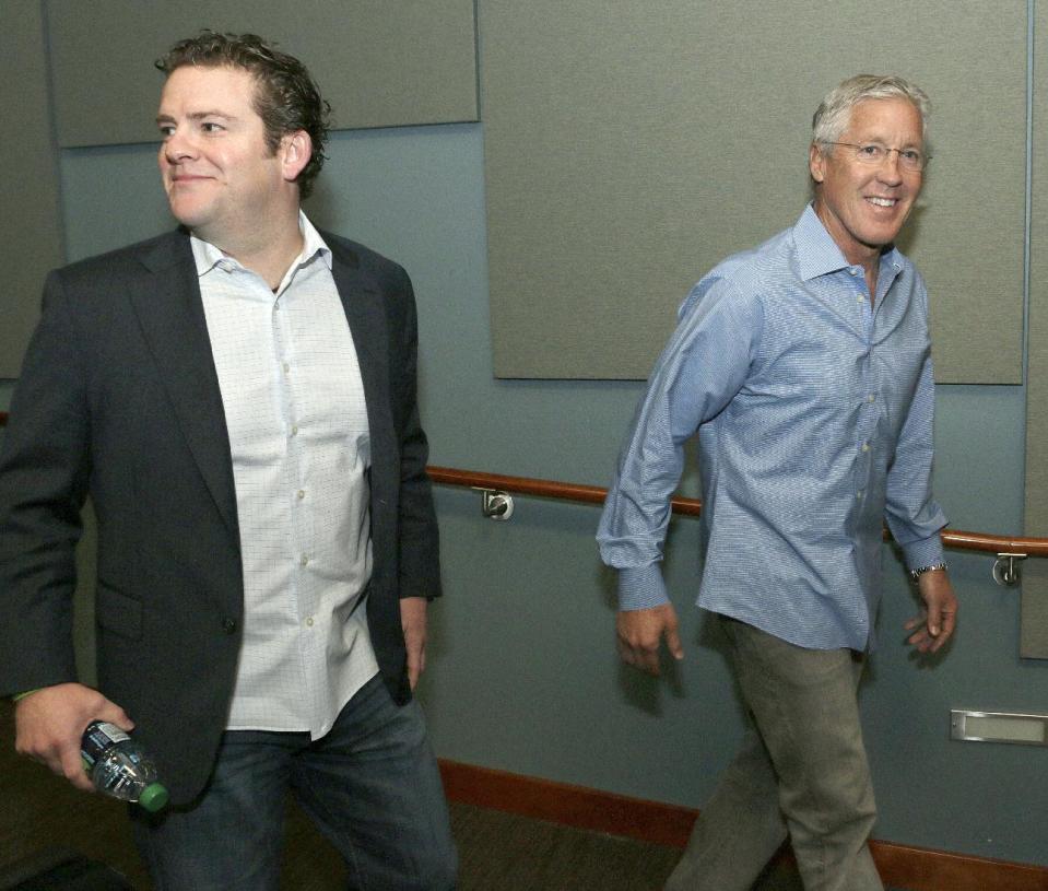 Seattle Seahawks general manager John Schneider, left, and Seattle Seahawks NFL football head coach Pete Carroll walk into a news conference to talk to reporters Friday, April 4, 2014, in Renton, Wash., after the team announced it had extended Carroll's contract. Carroll led the Seahawks to their first Super Bowl title over the Denver Broncos. (AP Photo/Marcus R. Donner)