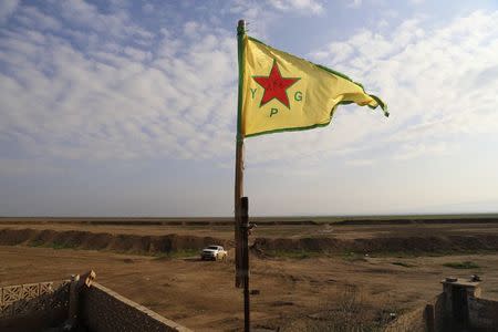 A Kurdish People's Protection Units (YPG) flag flutters on a lookout point between the Iraqi-Syrian border town of Rabia and the town of Snuny, north of Mount Sinjar December 20, 2014.REUTERS/Massoud Mohammed