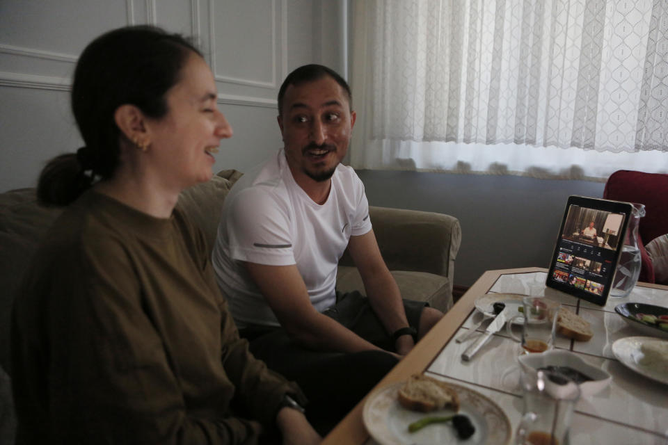 Alparslan Atas, 41, center, and his wife Gulistan, 38, left, laugh over breakfast at their home in Istanbul, while watching on a tablet, Sedat Peker, a Turkish fugitive crime boss on a video, Sunday, June 6, 2021. Sunday is the day the 49-year-old convicted crime ringleader posts the latest installation of his hour-long tell-all videos from his stated base in Dubai that have captivated Turkey and turned the mobster into an unlikely social media phenomenon. The convicted crime ringleader has been dishing the dirt on members of Turkish President Recep Tayyip Erdogan’s ruling party. The allegations range from drug trafficking and a murder cover-up to weapons transfers to Islamic militants. (AP Photo/Mehmet Guzel)