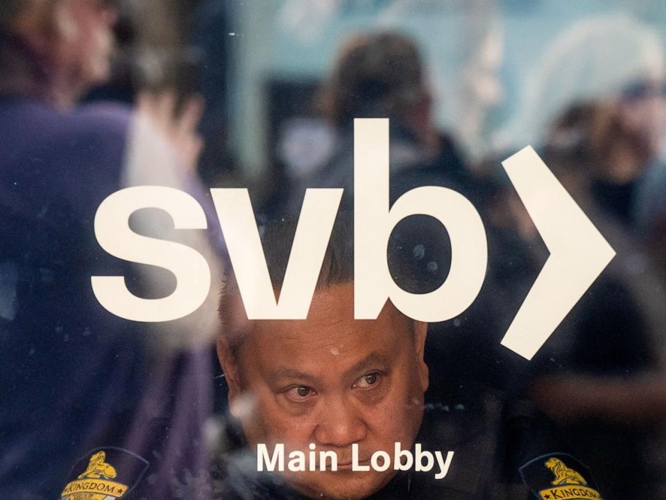 A security guard looks out as customers line up at Silicon Valley Bank (SVB) headquarters in Santa Clara, Calif., earlier this month. The demise of SVB was the second-largest bank failure, to date, in U.S. history. (Noah Berger/AFP/Getty Images - image credit)