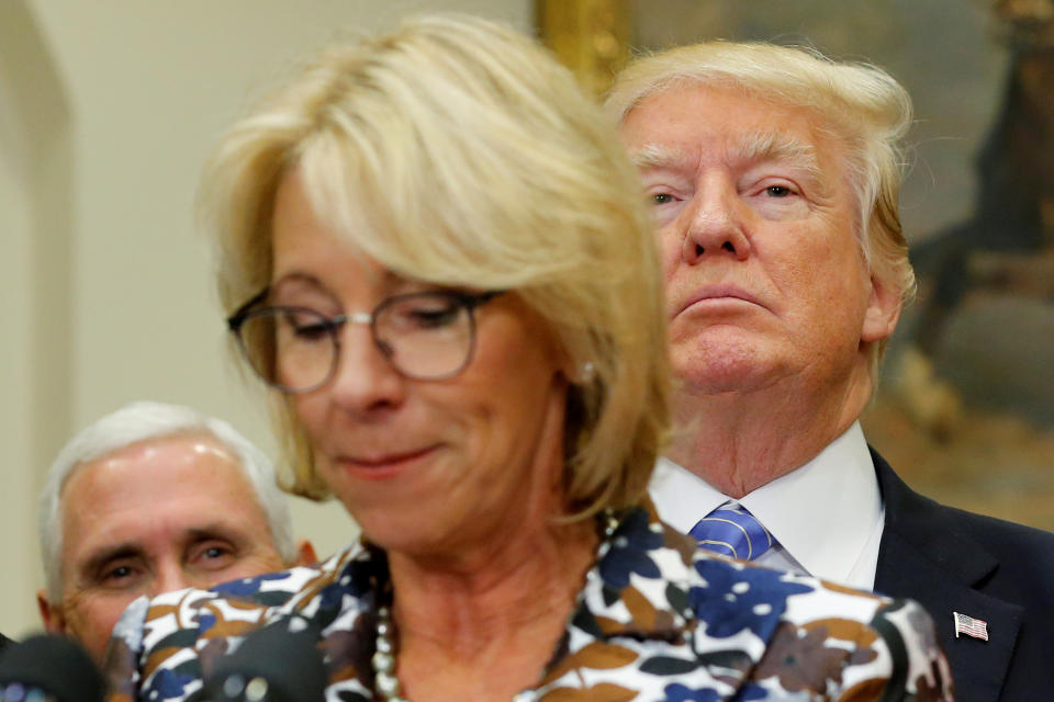 U.S. President Donald Trump (R, background) and Vice President Mike Pence (L) wait to interrupt Education Secretary Betsy DeVos as she speaks to students at a school choice event at the White House in Washington, U.S. May 3, 2017.  REUTERS/Jonathan Ernst