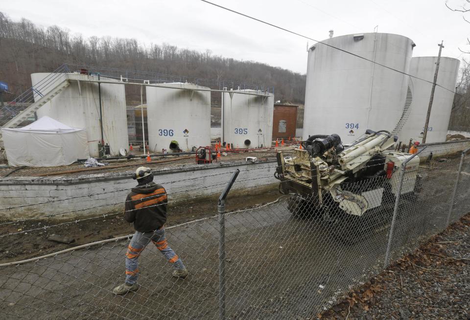 CORRECTS STATE TO W.VA. INSTEAD OF VA. - A worker moves a drilling machine around storage tanks at Freedom Industries storage facility in Charleston, W.Va., Monday, Jan. 13, 2014. The ban on tap water for parts of West Virginia was lifted on Monday, ending a crisis for a fraction of the 300,000 people who were told not to drink, wash or cook with water after a chemical spill tainted the water supply. Gov. Earl Tomblin made the announcement at a news conference, five days after people were told to use the water only to flush their toilets. (AP Photo/Steve Helber)