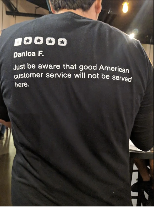 A person wearing a T-shirt with a text review about customer service