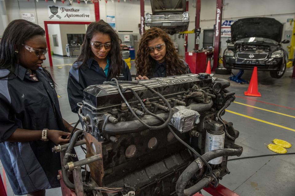 Talisia Muse, left, Felicitas Muniz and Kenny Vielman work on a diesel engine in automotive class at Maplewood High School. The students will now be able to service cars in an incorporated Firestone Complete Auto Care center.