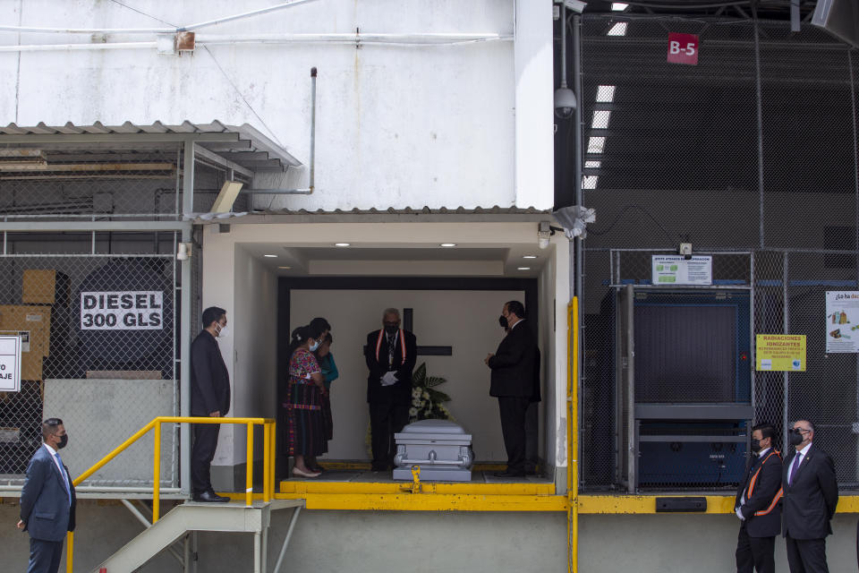 The parents of Pascual Melvin Guachiac Sipac stand next to their son's coffin, at left side, after his remains arrived to La Aurora International airport in Guatemala City, Friday, July 15, 2022. The 13-year-old was among a group of migrants who died of heat and dehydration in a trailer-truck abandoned by smugglers on the outskirts of San Antonio, Texas, on June 27. (AP Photo/Oliver de Ros)