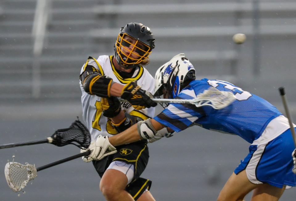 Upper Arlington's Tommy Janowicz (15) gets a shot off as he is hit by Hilliard Davidson's Mason Kaufman (31) during the Division I, Region 3 final May 27. The host Golden Bears won 17-4.