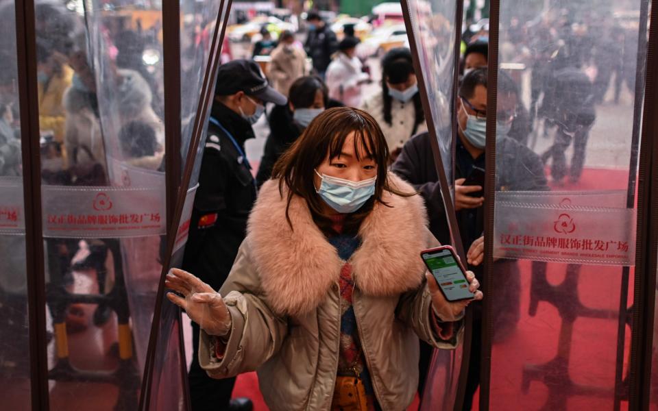 A woman wearing a face mask as a preventive measure against the Covid-19 coronavirus enters a shopping mall after showing her health code in Wuhan