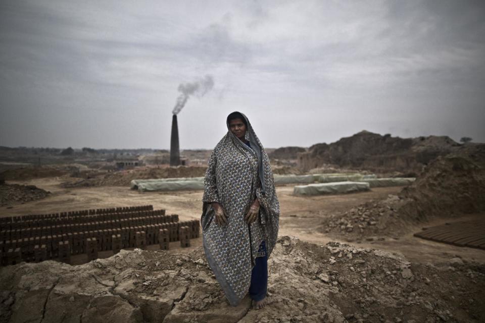 In this Monday, March 3, 2014, photo, Maqbool Ghulam, 35, a Pakistani brick factory worker, poses for a picture at the site of her work in Mandra, near Rawalpindi, Pakistan. Maqbool and her husband are in debt to their employer the amount of 250,000 rupees (approximately $2500). (AP Photo/Muhammed Muheisen)