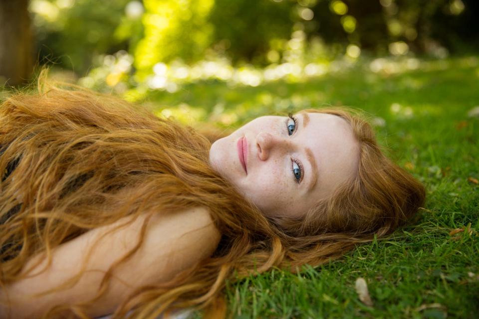 A redheaded model named Krissy from Stuttgart, Germany, lies on grass