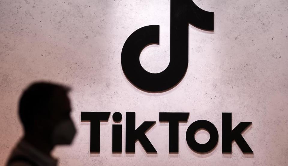 A person's silhouette can be seen on a wall with the TikTok music note logo.