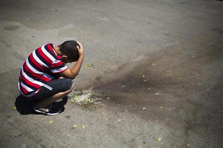 An Israeli boy looks at shrapnel at a parking lot in the Israeli southern city of Sderot after a rocket fired by Palestinian from Gaza Strip landed in the town April 21, 2014. REUTERS/Amir Cohen