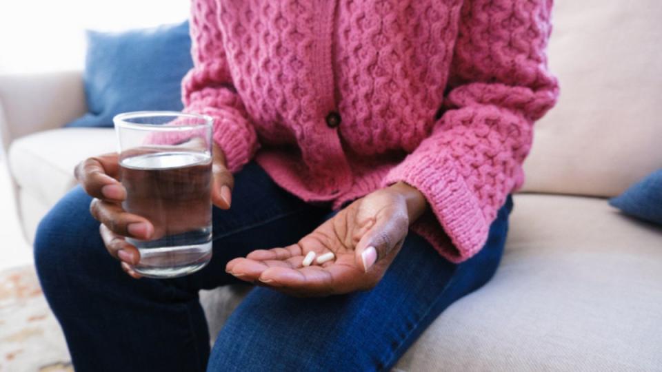 mature woman holding pills with glass of water