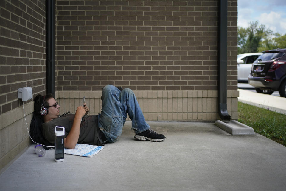 Chris Allan lays outside the Lee County Public Library while using the public WIFI, in Beattyville, Ky., Wednesday, July 29, 2020. As in other places, parents and officials are concerned about the virus, but dramatically limited internet access in many rural places also means kids could fall seriously behind if the pandemic keeps them home again. (AP Photo/Bryan Woolston)