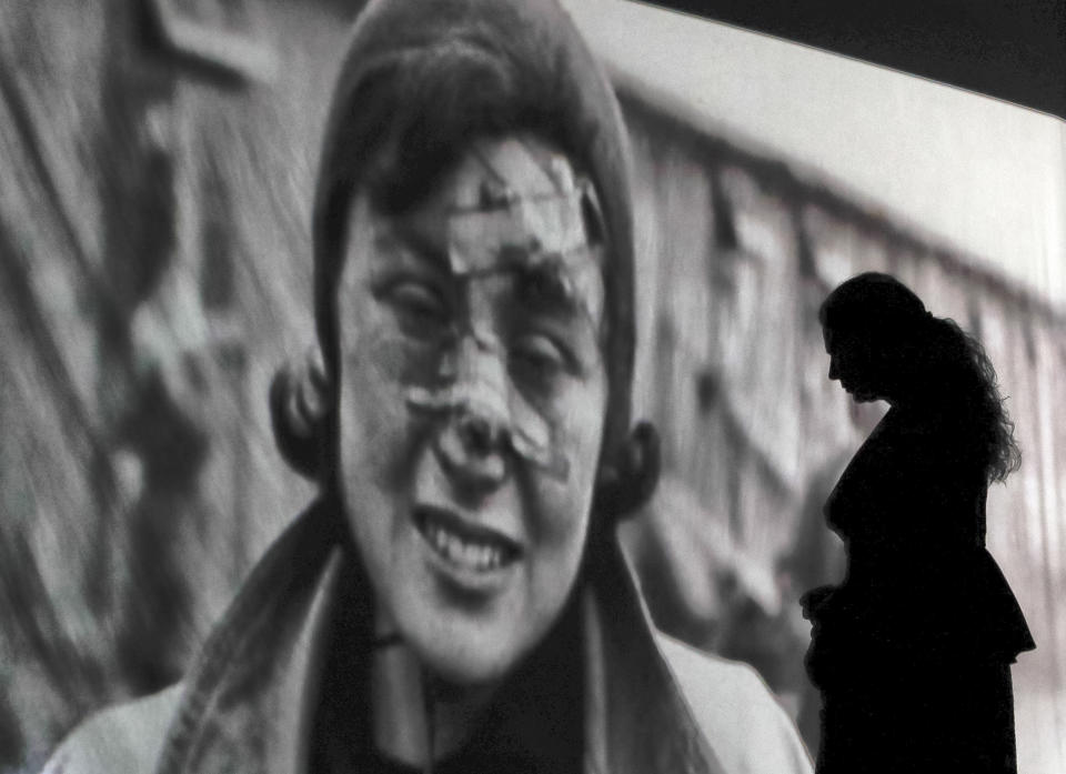 Silhouetted against an image of a death camp prisoner, an actress of the Romania's Jewish State Theatre rehearses the musical drama "The Lights of the Ghetto" a mix of music and stories by Holocaust survivors in Bucharest, Romania, Saturday, Jan. 26, 2019, a day before the premiere on International Holocaust Remembrance Day. About 280,000 Romanian Jews and 11,000 Romanian Roma, or Gypsies, were deported and killed during WWII when Romania was ruled by a pro-nazi regime. (AP Photo/Vadim Ghirda)