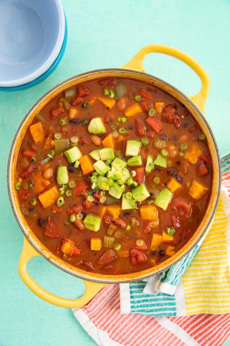 vegan chili topped with avocado cubes and sliced green onions