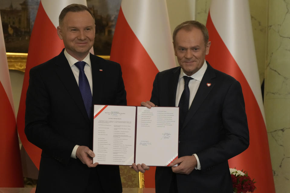 Poland's new Prime Minister Donald Tusk, right, and Poland's President Andrzej Duda pose for cameras during the swearing-in ceremony at the presidential palace in Warsaw, Poland, Wednesday, Dec. 13, 2023. Donald Tusk was sworn in by the president in a ceremony where each of his ministers was also taking the oath of office. (AP Photo/Czarek Sokolowski)