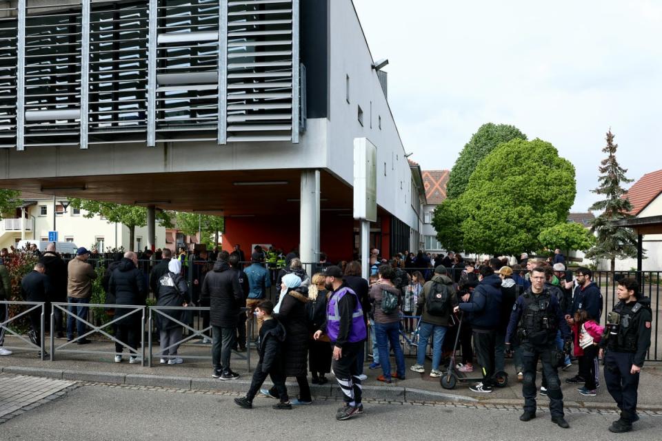 Pupils and parents gather outside a school among police forces in the eastern France city of Souffelweyersheim after two girls were wounded in a knife attack outside the school on Thursday (AFP via Getty Images)