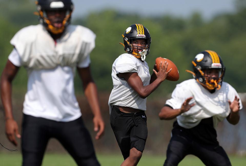 North quarterback Sigmund Felding, center, looks to pass during football practice Aug. 3 at North High School.