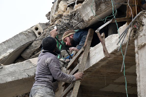 An injured man is helped by a resident to slide out of the rubble of a collapsed building following an earthquake in the town of Jandaris, in the countryside of Syria's northwestern city of Afrin in the rebel-held part of Aleppo province, on February 6, 2023. - Hundreds have been reportedly killed in north Syria after a 7.8-magnitude earthquake that originated in Turkey and was felt across neighbouring countries. (Photo by Rami al SAYED / AFP) (Photo by RAMI AL SAYED/AFP via Getty Images)