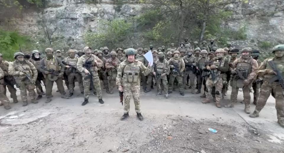 Evgeny Prigozhin gives a speech, flanked by around 50 men in combat gear holding rifles.