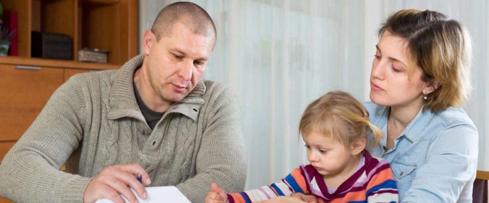 Upset couple with child sitting at the table with financial documents