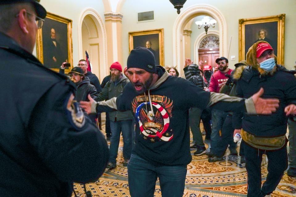 In this Jan. 6, 2021, file photo, Trump supporters, including Doug Jensen, center, confront U.S. Capitol Police in the hallway outside of the Senate chamber at the Capitol in Washington. Some followers of the QAnon conspiracy theory are now turning to online support groups and even therapy to help them move on, now that it's clear Donald Trump's presidency is over.