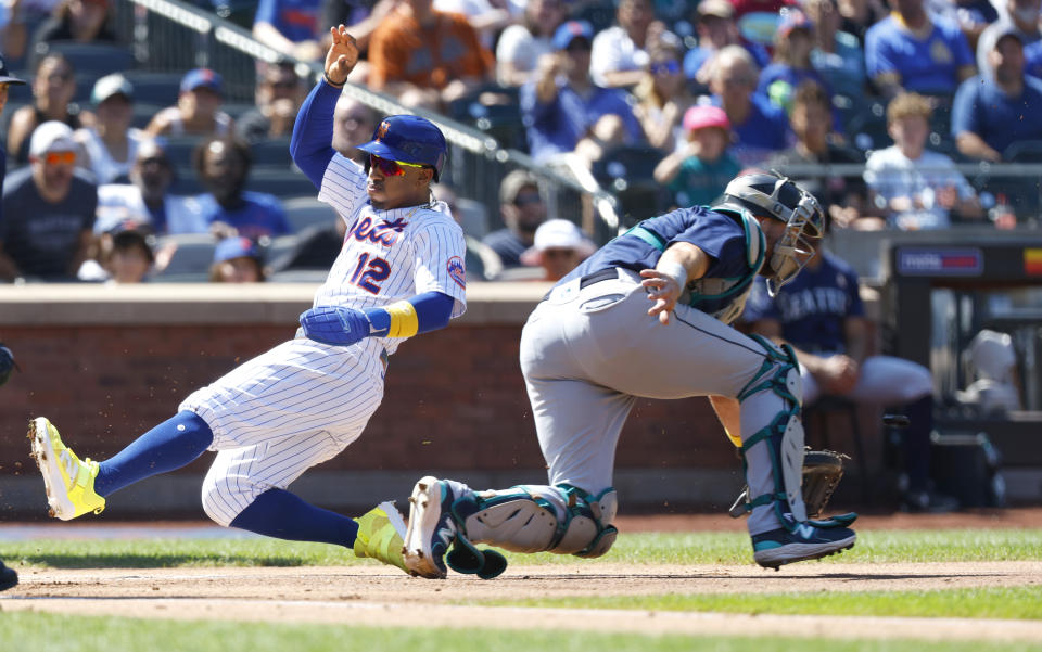 New York Mets' Francisco Lindor (12) beats the throw to Seattle Mariners catcher Cal Raleigh, right, to score during the first inning of a baseball game, Sunday, Sept. 3, 2023, in New York. (AP Photo/Noah K. Murray)