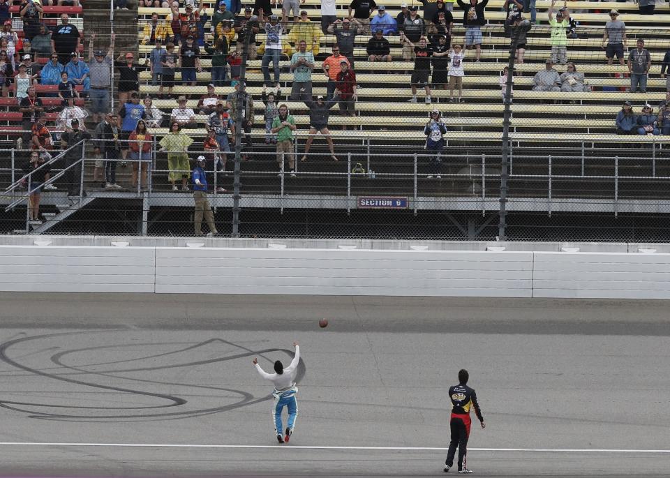 Bubba Wallace tosses a football into the stands during a rain delay at the NASCAR cup series auto race at Michigan International Speedway, Sunday, June 9, 2019, in Brooklyn, Mich. The race has been rescheduled for Monday. (AP Photo/Carlos Osorio)
