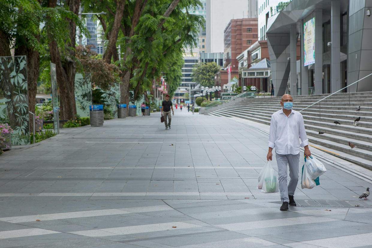 A man in a face mask seen carrying groceries along Orchard Road on 7 April 2020, the first day of Singapore&#39;s month-long circuit breaker period. (PHOTO: Dhany Osman / Yahoo News Singapore)