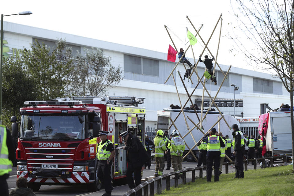 Police and fire services at the scene, outside Broxbourne newsprinters as protesters continue to block the road, in Broxbourne, Hertfordshire, England, Saturday, Sept. 5, 2020. Environmental activists have blockaded two British printing plants, disrupting the distribution of several national newspapers. The group Extinction Rebellion said it targeted printworks at Broxbourne, north of London, and Knowsley in northwest England that are owned by Rupert Murdoch’s News Corp. Dozens of protesters locked themselves to vehicles and bamboo scaffolding to block the road outside the plants. The facilities print Murdoch-owned papers The Sun and The Times, as well as the Daily Telegraph, the Daily Mail and the Financial Times. (Yui Mok/PA via AP)