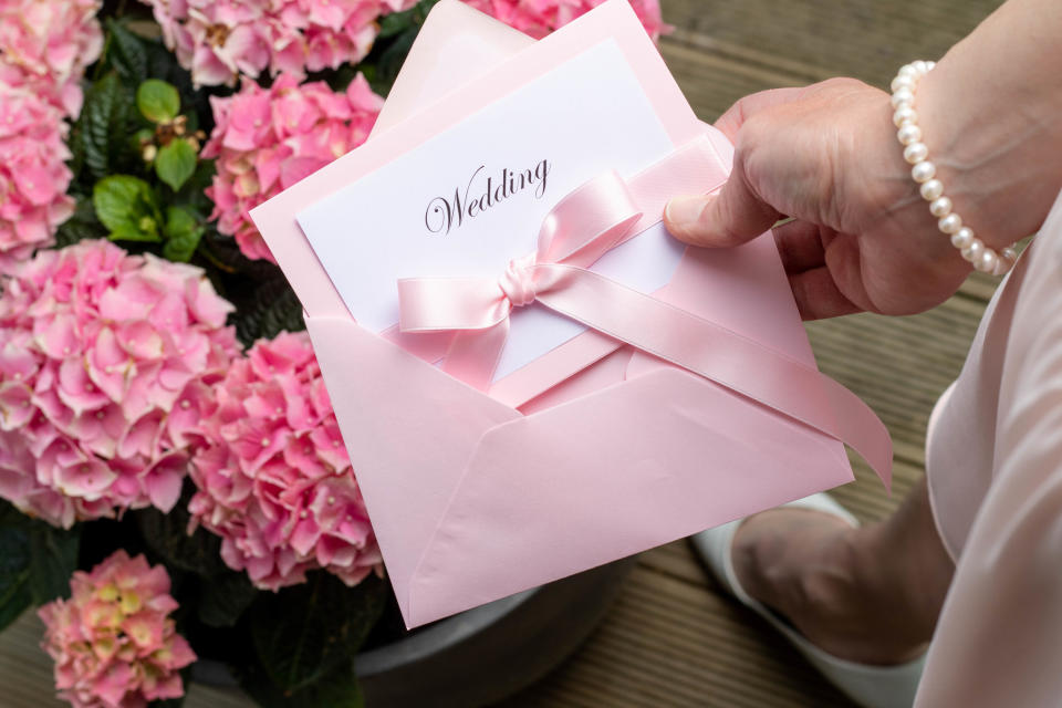 Wedding invitations in a pink envelope against pink flowers