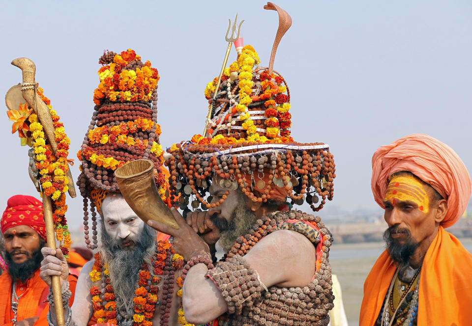 A Naga Sadhu, wearing prayer beads, plays a traditional instrument