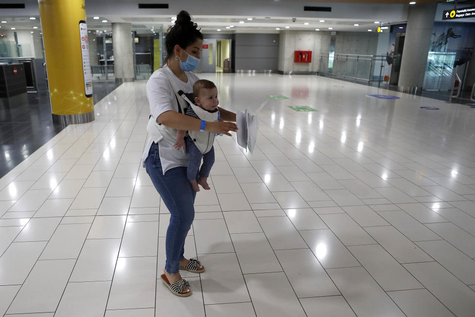 A mother and baby passengers from Israel holds her documents after arriving at Cyprus' main airport in Larnaca, on Tuesday, June 9, 2020. Cyprus re-opened its airports on Tuesday to a limited number of countries after nearly three months of commercial air traffic as a result of a strict lockdown aimed at staving off the spread of COVID-19. (AP Photo/Petros Karadjias)