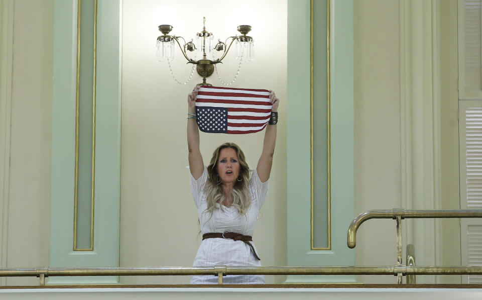 Tara Thornton, who opposes a measure to tighten the rules on giving exemptions for vaccinations, stands in protest after the bill approved by the Assembly in Sacramento, Calif., Tuesday, Sept. 3, 2019. The bill SB276, by Democratic Sen. Richard Pan of Sacramento, would allow state public health officials to investigate doctors who grant more than five medical exemptions in a year and schools with vaccination rates of less than 95%. (AP Photo/Rich Pedroncelli)