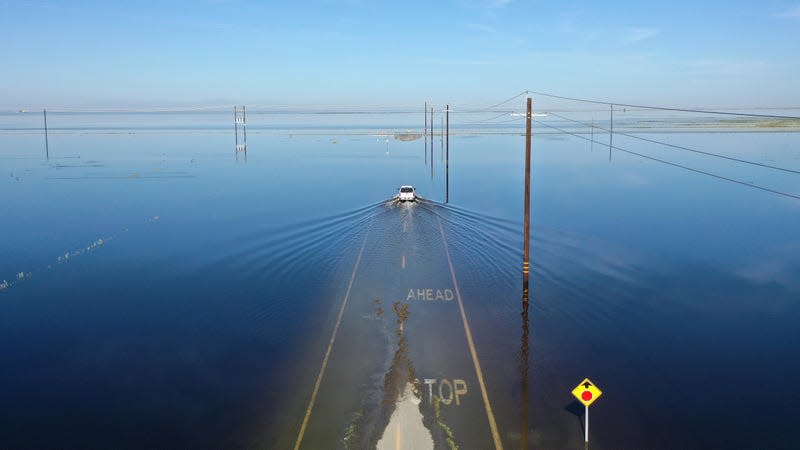 A car drives through floodwaters in the reemerging Tulare Lake near Corcoran, CA on April 27, 2023. 
