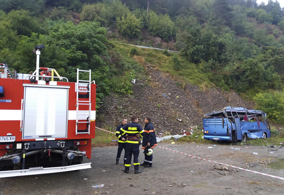 In this handout photo provided by the Bulgarian Interior Ministry, firefighters near the scene where a bus crashed and overturned, near the town of Svoge, Saturday, Aug. 25, 2018. Bulgaria's health minister says a tourist bus has flipped over on a highway near Sofia, the capital, killing at least 15 people and leaving 27 others injured. Police said a bus carrying tourists on a weekend trip to a nearby resort overturned and then fell down a side road 20 meters (66 feet) below the highway. (Bulgarian Interior Ministry via AP)