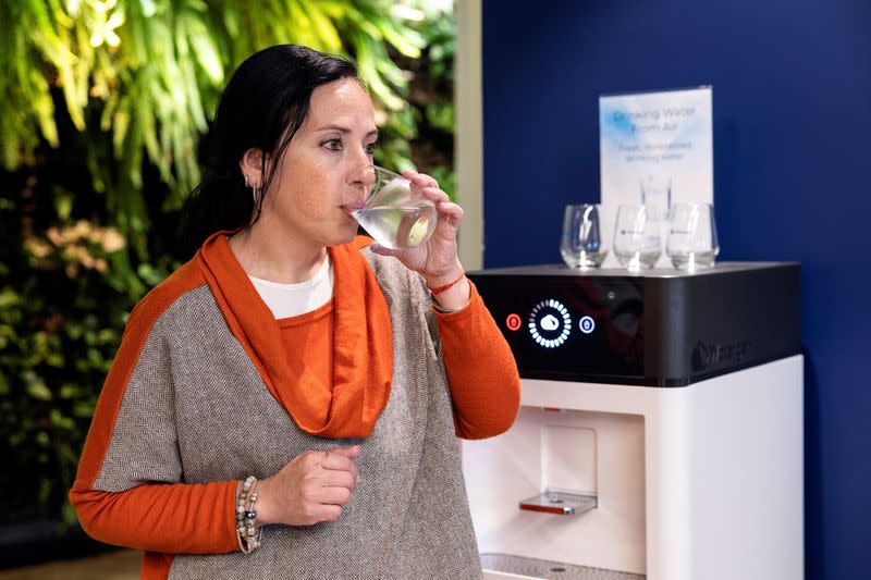 A worker tastes drinking water, that has been extracted from the air, at the office of Watergen, in Petah Tikva