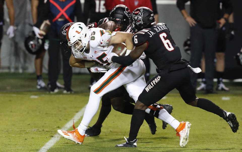 Miami tight end Will Mallory (85) is tackled by North Carolina State's Jakeen Harris (6), Tyler Baker-Williams (13) and Cecil Powell (4) during the first half of an NCAA college football game Friday, Nov. 6, 2020, in Raleigh, N.C. (Ethan Hyman/The News & Observer via AP, Pool)