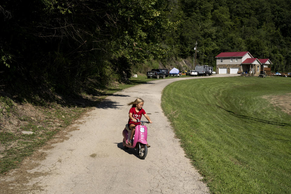 Image: Sailer Noble, 6, rides her electric bike from the camper she and parents have been staying in on Aug. 19, 2022 near Jackson, Ky., since their house was damaged in the flood. (Michael Swensen for NBC News)