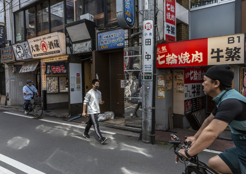 TOKYO, JAPAN - JUNE 20: A man wearing a face mask walks through the Takadanobaba area on June 20, 2021 in Tokyo, Japan. The Japanese government is expected to end the COVID-19 state of emergency on Sunday in several prefectures including Tokyo and Osaka, with the exception of Okinawa. As concern continues to mount over the feasibility of hosting events during the COVID-19 pandemic, Tokyo Governor Yuriko Koike, on Saturday, cancelled all public viewing sites for the upcoming Tokyo 2020 Olympic Games. (Photo by Yuichi Yamazaki/Getty Images)