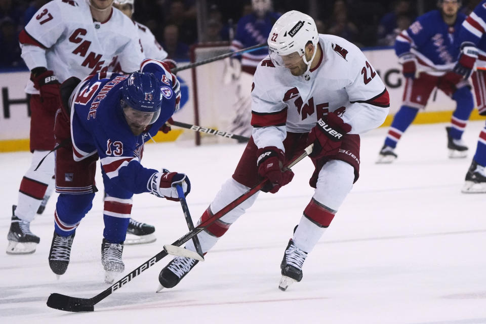 New York Rangers left wing Alexis Lafrenière (13) and Carolina Hurricanes defenseman Brett Pesce (22) vie for the puck during the second period of an NHL hockey game Tuesday, April 12, 2022, in New York. (AP Photo/Bebeto Matthews)