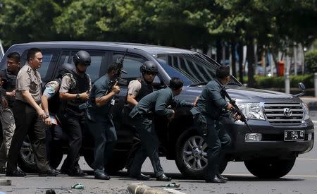 Indonesian police hold rifles while walking behind a car for protection in Jakarta January 14, 2016. REUTERS/Beawiharta