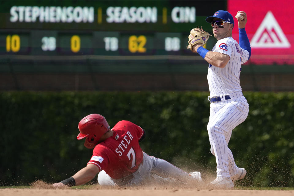 Chicago Cubs second baseman Nico Hoerner, right, throws out Cincinnati Reds' Tyler Stephenson at first base after forcing out Spencer Steer, left, at second base during the eighth inning of a baseball game in Chicago, Sunday, May 28, 2023. (AP Photo/Nam Y. Huh)