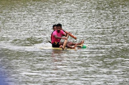 Two boys use two cricket bats to paddle a handmade boat on a flooded road in Bulathsinhala village, in Kalutara, Sri Lanka May 27, 2017. REUTERS/Dinuka Liyanawatte