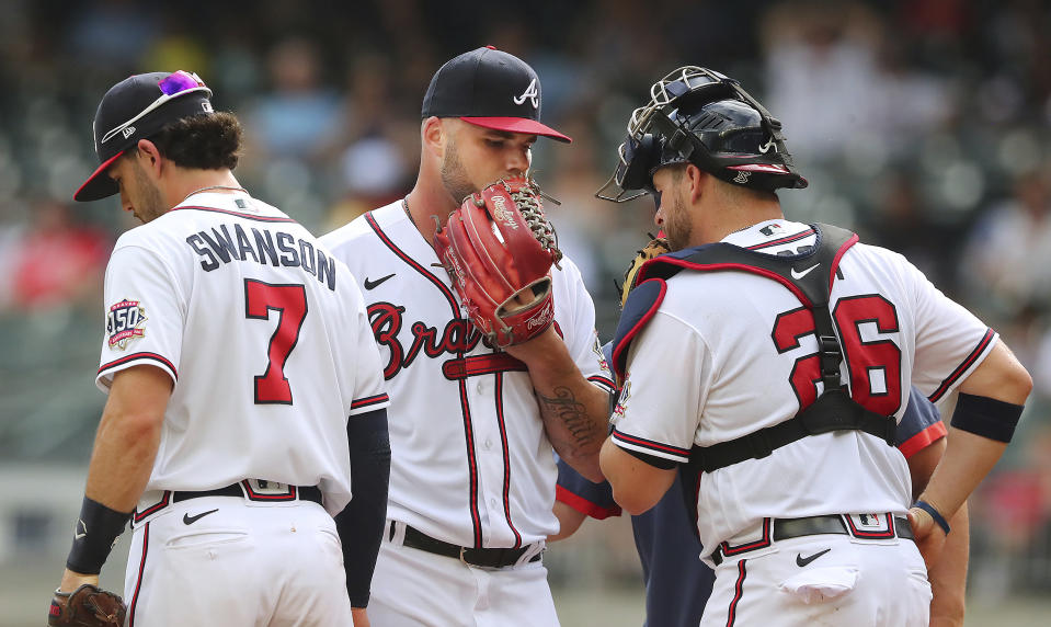 Atlanta Braves starting pitcher Bryse Wilson confers with catcher Stephen Vogt and Dansby Swanson during the first inning against the San Diego Padres in the second game of a baseball doubleheader Wednesday, July 21, 2021, in Atlanta. (Curtis Compton/Atlanta Journal-Constitution via AP)