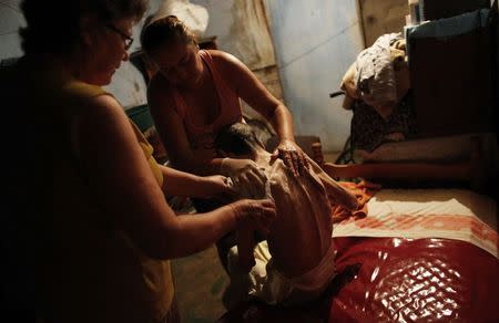Cerebrovascular accident (CVA) patient Pedro, sits on his bed before being washed with the help of his daughter Daniela (R), 38, and wife Maria Do Carmo, 70, inside their house in Brasilandia slum, of which they are without water for 13 hours a day, in Sao Paulo February 11, 2015. REUTERS/Nacho Doce