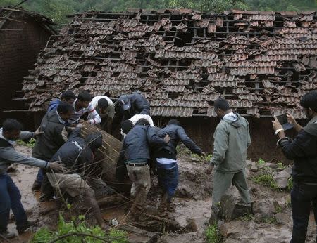 Rescue workers and volunteers clear the debris from the site of a landslide at Malin village in Maharashtra July 30, 2014. REUTERS/Stringer